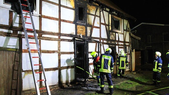 Feuerwehrleute löschen ein brennendes Wohnhaus.