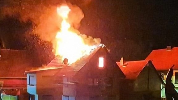 Der Dachstuhl eines Hauses in Flammen.
