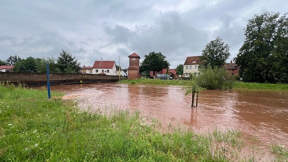 Der Fluss Helme mit sehr viel Wasser, daneben Häuser.