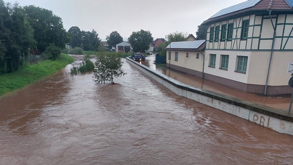 Der Fluss Helme mit sehr viel Wasser, daneben Häuser.