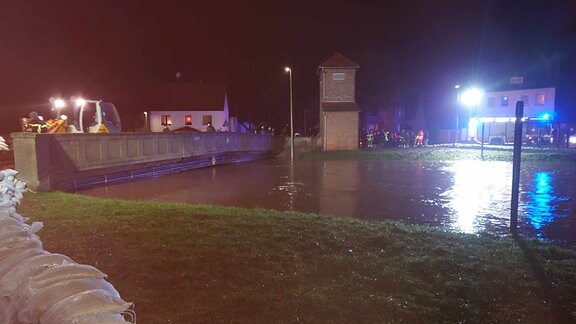 Am Ufer der Helme in Sundhausen sind an einer Brücke Sandsäcke gegen Hochwasser gestapelt.