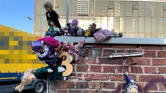 Puppen liegen auf und hängen an einer Mauer in Nordhausen.