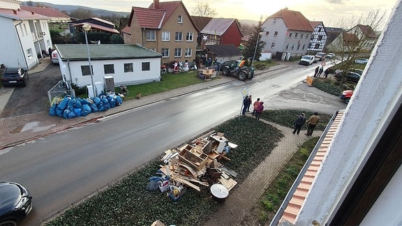 Blick auf eine Straße mit viel Sperrmüll. Nach dem Hochwasser haben die Aufräumarbeiten in Windehausen bei Nordhausen begonnen.