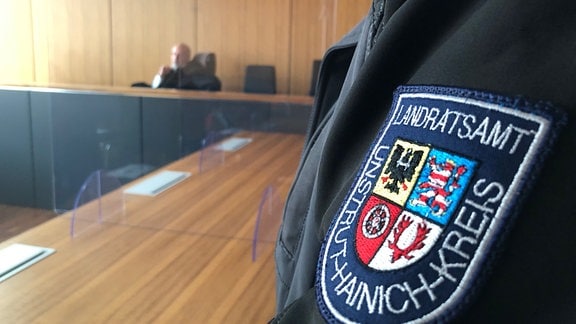 Ein Jackenärmel mit einem Wappen in einem Gerichtssaal