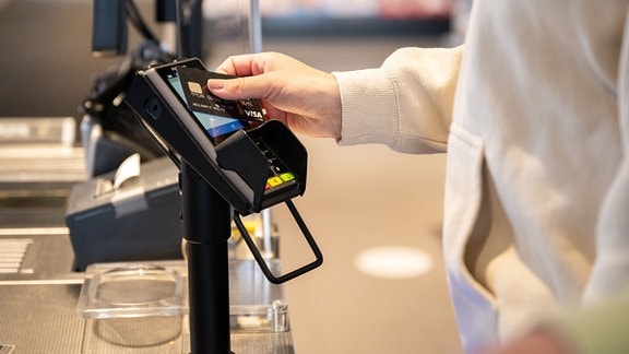 Eine Frau bezahlt mit einer Kreditkarte im Supermarkt