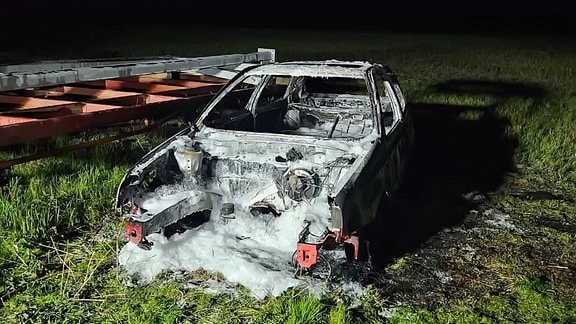 Ein ausgebranntes Auto mit Feuerwehrschaum