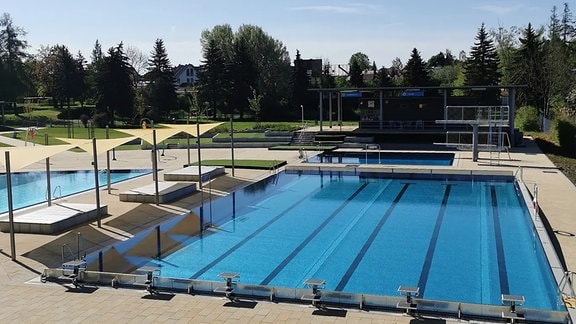 Wasserbecken im Freibad am Schwanenteich mit Startblöcken und Sonnensegeln sowie Sprungtum