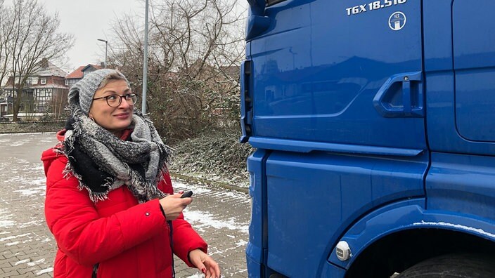 Eine Frau neben einem groÃen blauen LKW.