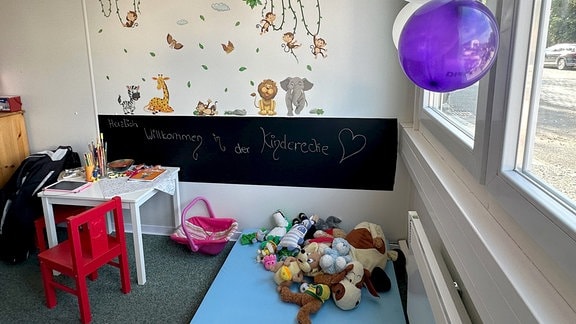 Blick in das Kinderspielzimmer mit Plüschtieren, kleinem Tisch und kleinem Stuhl und Luftballons in der Wärmestube Mühlhausen