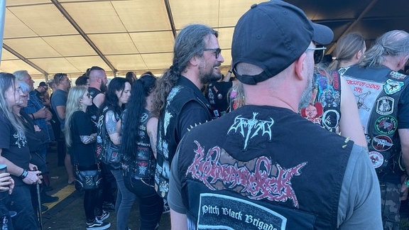 Heavy-Metal-Fans stehen in einem großen Zelt.