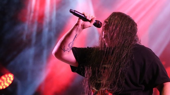 Ein Sänger mit langen Haaren bei einem Konzert.