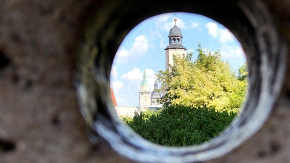 Blick auf drei Türme durch ein Steinloch