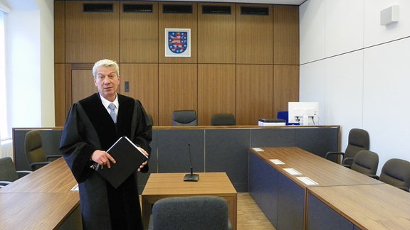 Ein Richter steht mitten in einem Gerichtstsaal.