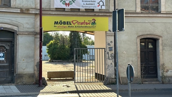 Zwei große Plakate hängen über dem Tor einer Hofeinfahrt. Das obere weist den Weg zum neuen Domizil der Kirmesgemeinde.