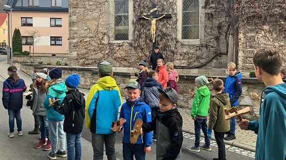Kinder stehen mit Holzklappern vor einer Kirche in Wendehausen im Unstrut-Hainich-Kreis