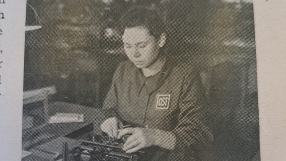 Ein Foto einer Zwangsarbeiterin die an einer Maschiene arbeitet.