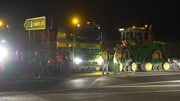 Landwirte blockieren mit ihren Fahrzeugen eine Autobahnauffahrt. 