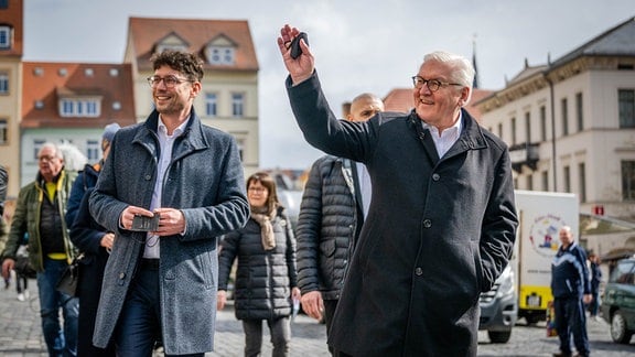 Bundespräsident Frank-Walter Steinmeier (r.) winkt bei einem Spaziergang über den Markt mit André Neumann