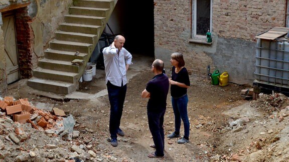 Drei Menschen stehen in einer Baustelle in Altenburg.