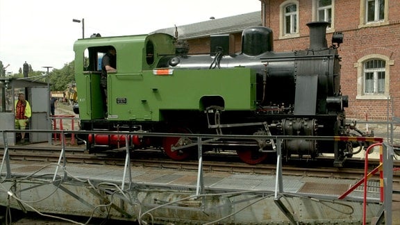 Eine historische Dampflok steht auf einem Gleis.