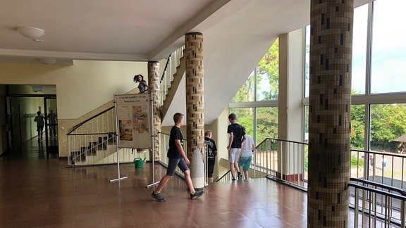 Schüler laufen in einem Treppenhaus ein Treppe hinunter