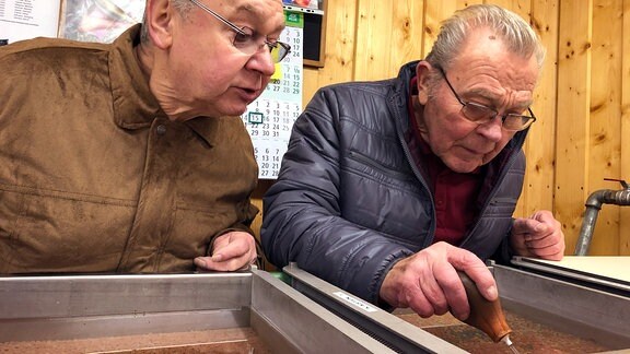 Stefan Franke und Manfred Schmidt gucken in die Brutrinne und suchen vom Pilz befallene Eier