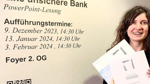 Die Gewinnerin des Anne Biermann Preises Stefanie Schröder steht mit der Auszeichnung in der Hand an einer Wand.