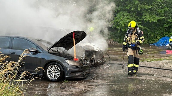 Einsatzkräfte der Feuerwehr löschen brennende Autos.