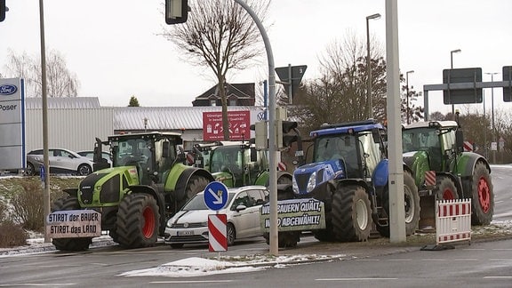 Mehrere Traktoren stehen in der Zufahrt zu einem Unternehmen.