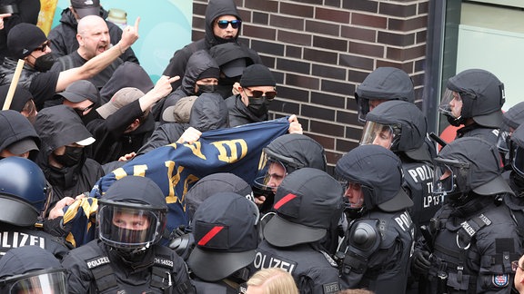 Zumeist schwarz gekleidete Teilnehmer protestieren an 1. Mai 2023 in Gera gegen eine Kundgebung der teils rechtsextremen Initiative "Aufbruch Gera" und stehen sich Polizeibeamten gegenüber.