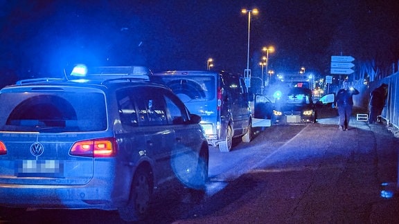Polizeiautos mit Blaulicht stehen in einer Straße vor einem BMW, der auf der falschen Straßenseite steht. 
