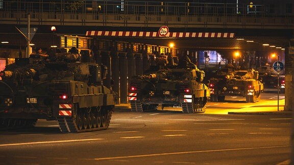 Mehrere Leopard-2-Panzer der Bundeswehr fahren unter einer Brücke in Gera hindurch