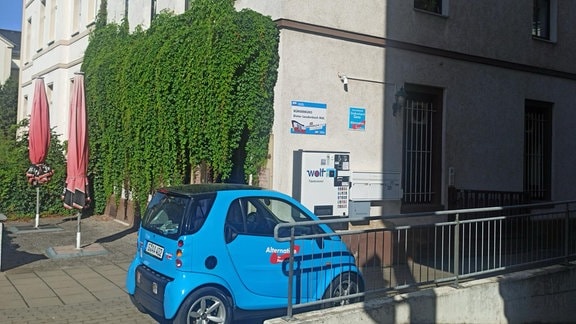 Ein blaues Auto steht vor einem Haus.