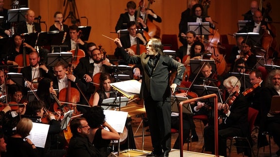 Ein Dirigent steht inmitten eines Orchesters
