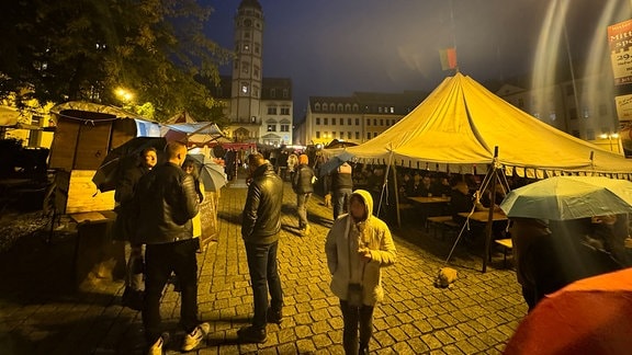 Menschen tummeln sich an einem Abend auf dem Rathausplatz in Gera