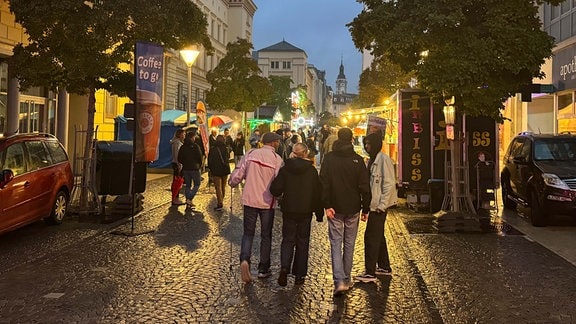 Menschen schlendern durch eine Straße in Gera, in der mehrere Stände stehen