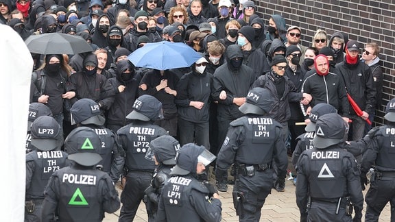 Zumeist schwarz gekleidete Teilnehmer protestieren gegen die sogenannte Montagsdemonstration und stehen sich am Rande der Montagsdemonstration Polizeibeamten gegenüber.