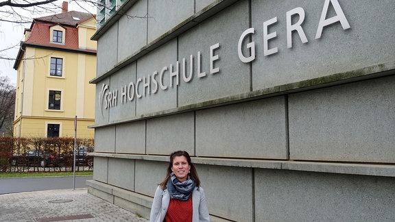 Eine Frau steht vor der Hochschule für Gesundheit in Gera