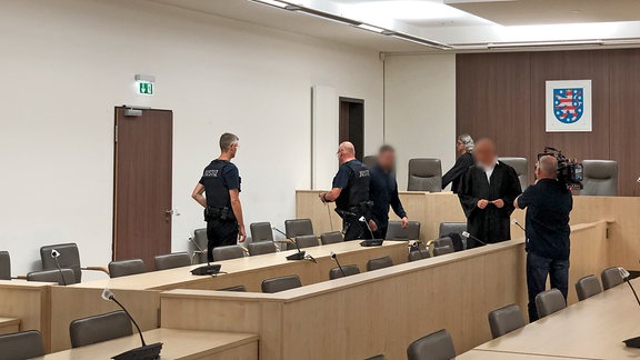 Justizbeamte, der Angeklagte, Richter und Journalisten im einem Gerichtssaal in Gera.