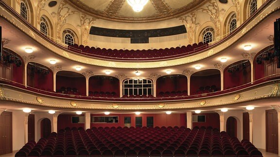 Ein Theatersaal mit Beleuchtung und roten Sitzen.