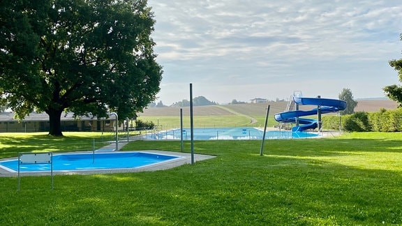 Schwimmbecken eines Freibads umgeben von Landschaft.