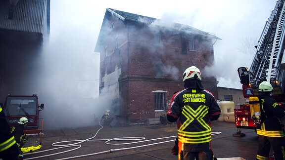 Feuerwehrmänner nähern sich einem Haus, aus dem Qualm dringt