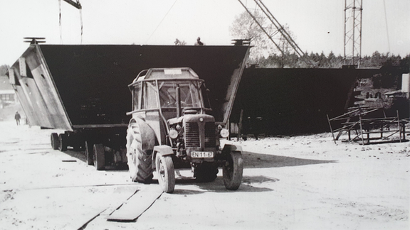Eine schwarz-weiß Fotografie zeigt einen Stahlkasten mit einem Trecker vorn dran.