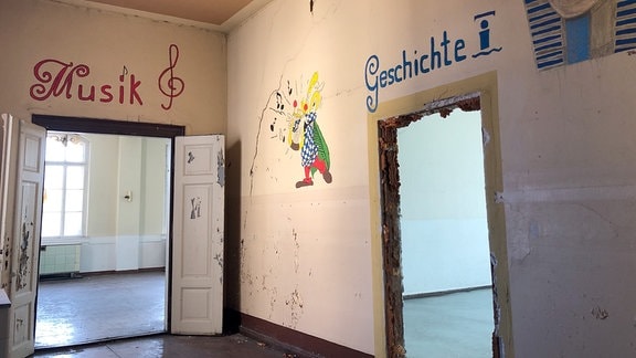 Leerstehende Gebäude in Weida: Blick in ein verlassenes Schulgebäude mit Türen "Geschichte" und "Musik"