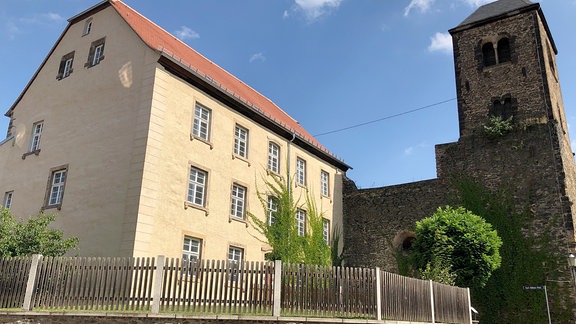 Leerstehende Gebäude in Weida: Historisches Gebäude neben einem Turm aus Natürstein.