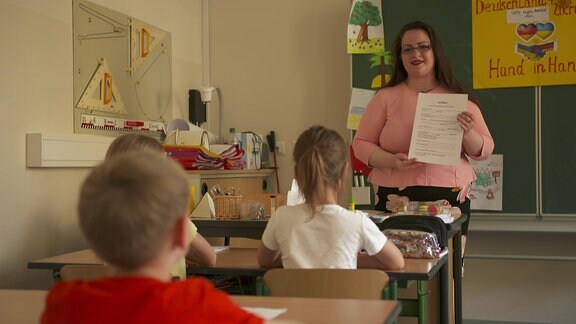 Eine Lehrerin zeigt ein Papier.