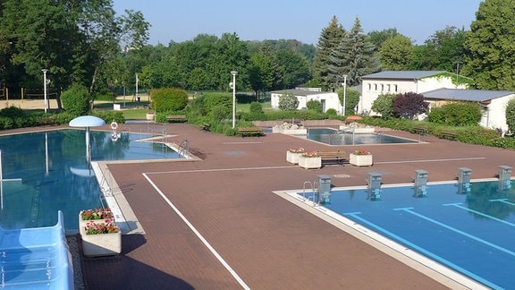 Schwimmbecken mit Rutsche und Liegemöglichkeiten sowie einem Beach-Volleyballfeld.