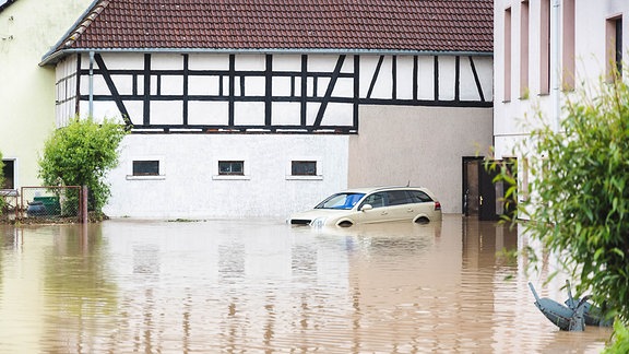 Im Ort Hilbersdorf im Landkreis Greiz steht der Bereich vor einem Wohngebäude mit einem Auto unter Wasser.