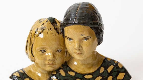 Farbig glasierte Keramikbüste zweier Mädchen.
