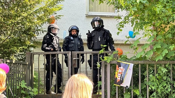 Polizisten in Einsatzuniformen stehen vor einem Gebäude.